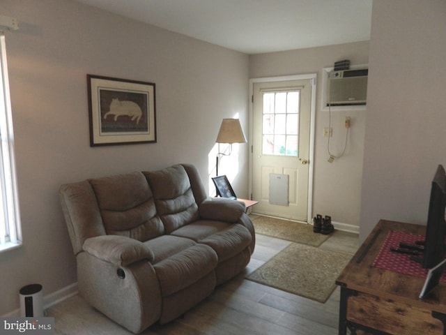 living room with light hardwood / wood-style floors and a wall unit AC