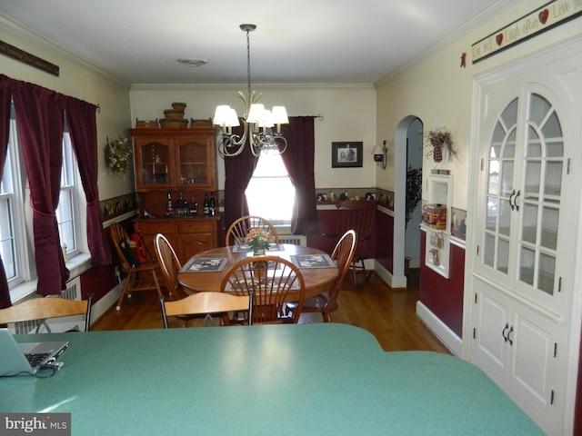 dining area featuring ornamental molding, dark wood-type flooring, and a chandelier