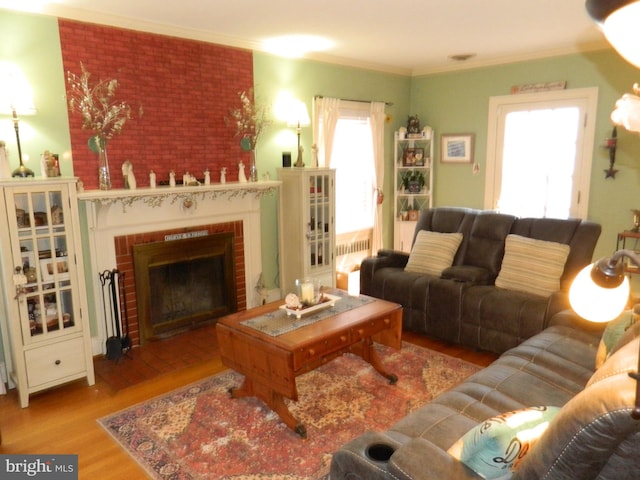 living room with a brick fireplace, light hardwood / wood-style flooring, and ornamental molding