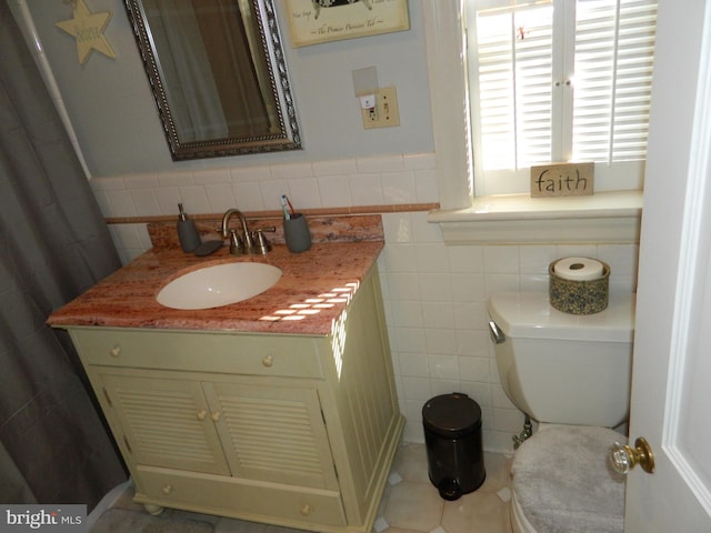 bathroom with tile patterned flooring, vanity, tile walls, and toilet