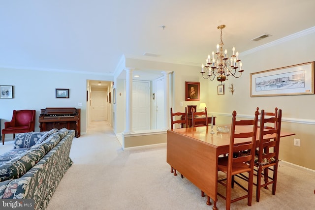 carpeted dining space featuring ornamental molding, a notable chandelier, and decorative columns