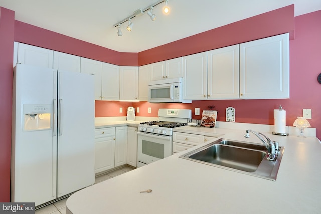 kitchen with white appliances, rail lighting, light tile patterned floors, sink, and white cabinetry