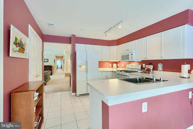 kitchen featuring white appliances, white cabinets, kitchen peninsula, and sink