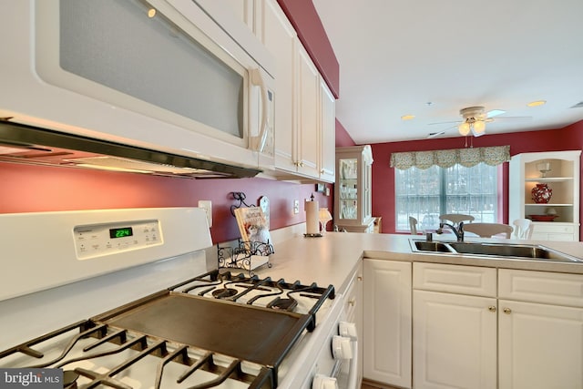 kitchen with kitchen peninsula, ceiling fan, white cabinets, stove, and sink