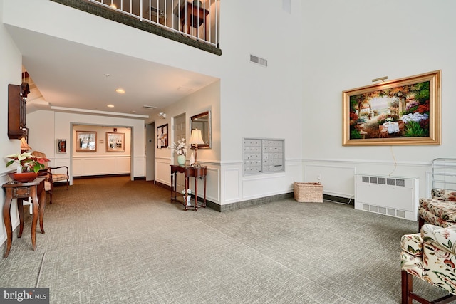 living area with a mail area, carpet, and radiator