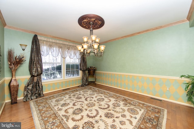 dining room with hardwood / wood-style flooring, crown molding, and a chandelier