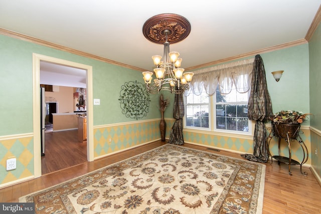 dining room with wood-type flooring, crown molding, and an inviting chandelier