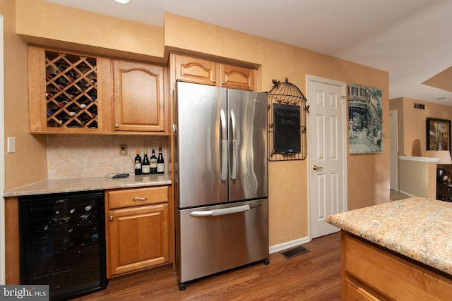 kitchen with wine cooler, stainless steel fridge, light stone counters, and tasteful backsplash