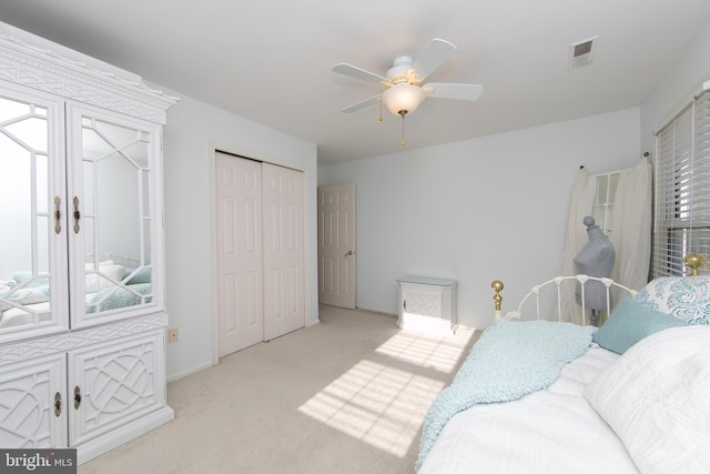 bedroom featuring ceiling fan, light carpet, and a closet