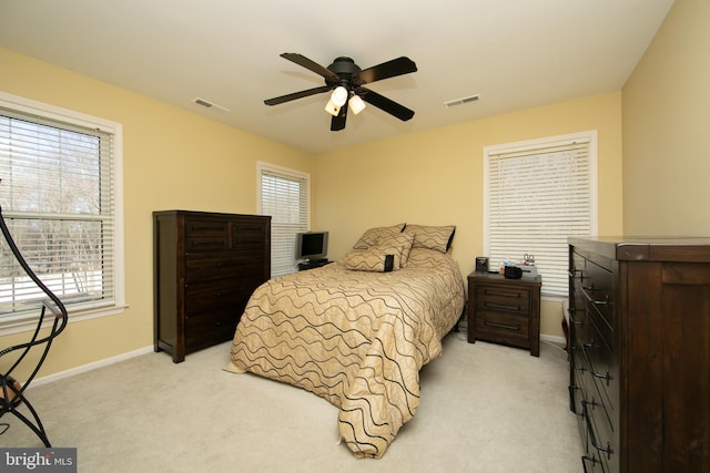 bedroom featuring ceiling fan, light colored carpet, and multiple windows