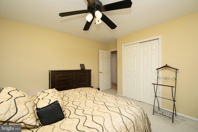 bedroom with ceiling fan, light colored carpet, and a closet