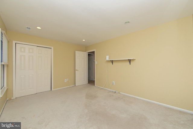 unfurnished bedroom with light colored carpet and a closet