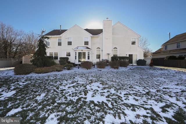 snow covered rear of property featuring a storage shed