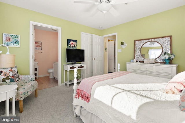 carpeted bedroom with ensuite bathroom and ceiling fan