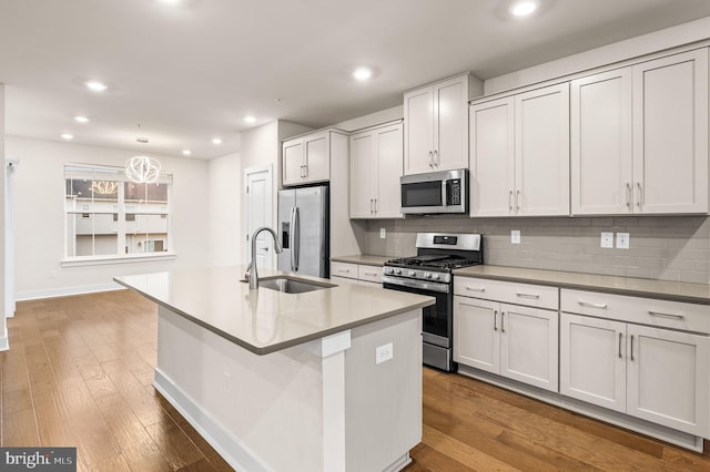 kitchen with a center island with sink, white cabinets, sink, tasteful backsplash, and stainless steel appliances