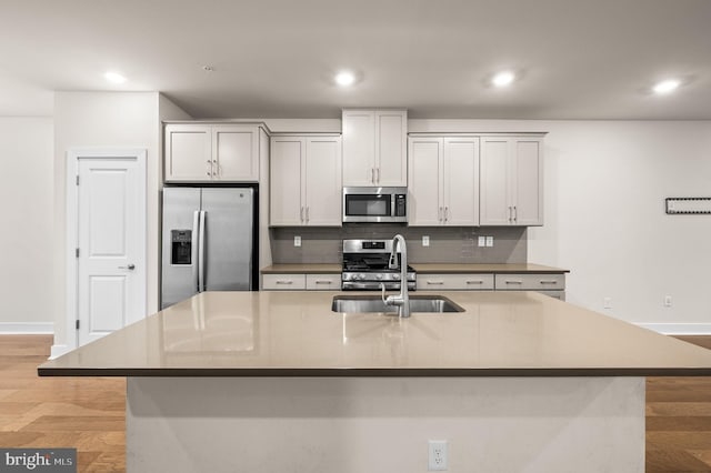 kitchen featuring stainless steel appliances, white cabinetry, and a center island with sink