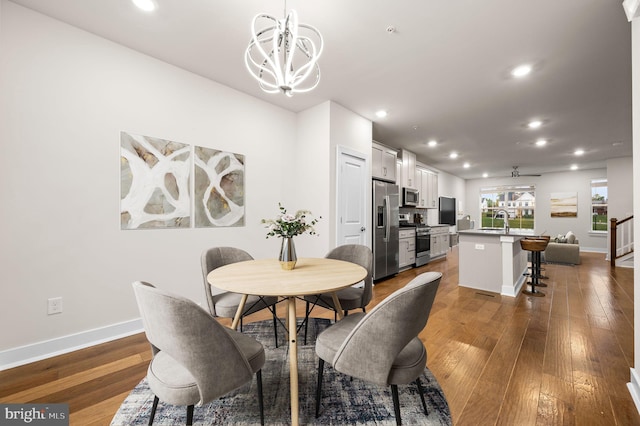 dining space with hardwood / wood-style floors, sink, and an inviting chandelier