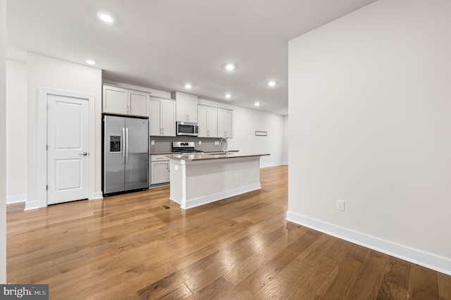 kitchen featuring white cabinetry, sink, stainless steel appliances, a kitchen bar, and a kitchen island with sink