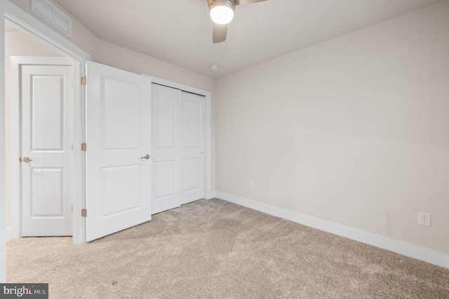 unfurnished bedroom featuring ceiling fan, a closet, and light carpet