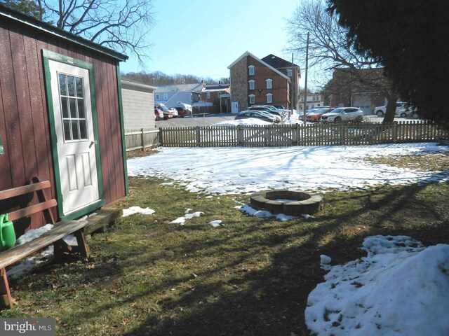 yard layered in snow featuring an outdoor structure and a fire pit