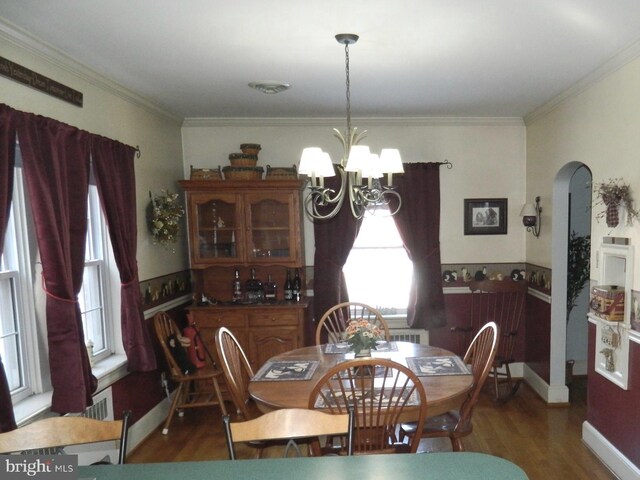 dining space featuring ornamental molding, dark wood-type flooring, and a chandelier