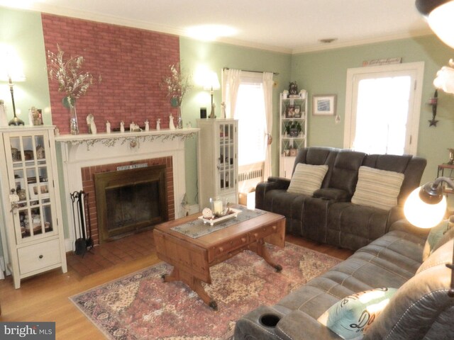 living room featuring ornamental molding, a brick fireplace, and light wood-type flooring