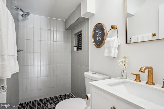 bathroom featuring toilet, a tile shower, and vanity