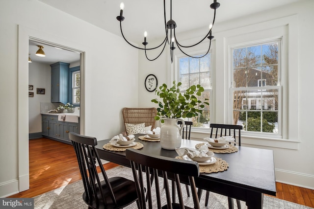 dining space with hardwood / wood-style floors and a notable chandelier