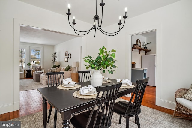 dining space with hardwood / wood-style flooring and a notable chandelier