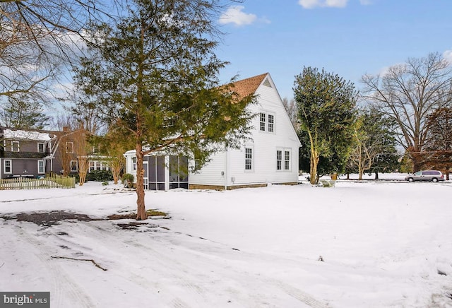 snow covered property featuring a sunroom