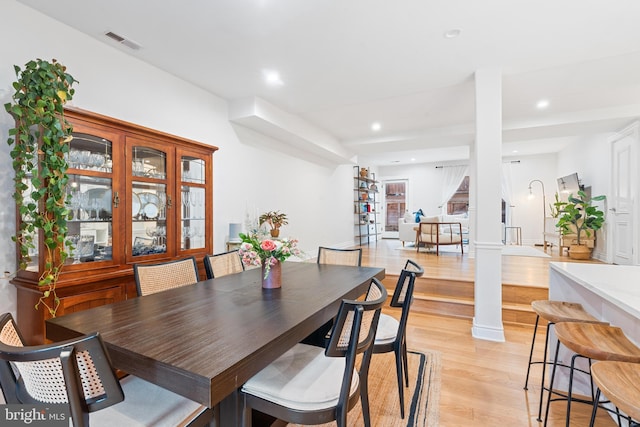 dining space featuring light hardwood / wood-style flooring and decorative columns