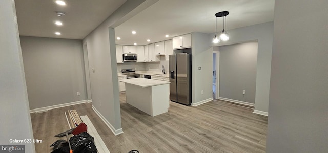 kitchen featuring a center island, pendant lighting, sink, appliances with stainless steel finishes, and white cabinets