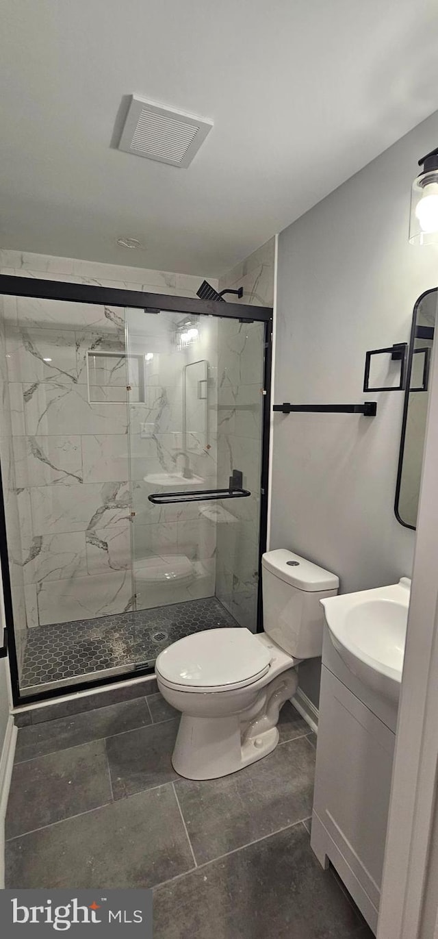 bathroom with toilet, vanity, and a shower with door