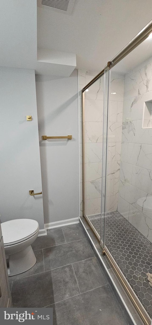 bathroom featuring a shower with shower door and toilet