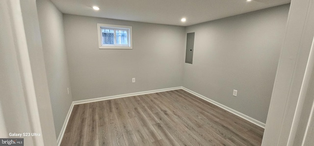 empty room with electric panel and hardwood / wood-style flooring