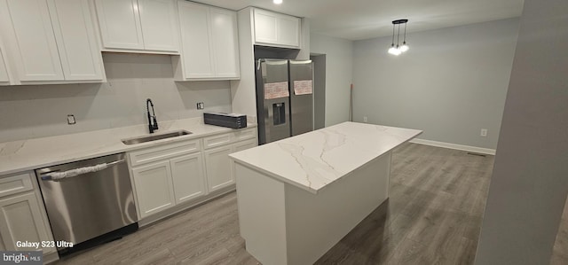 kitchen featuring a kitchen island, sink, stainless steel appliances, white cabinets, and light stone counters