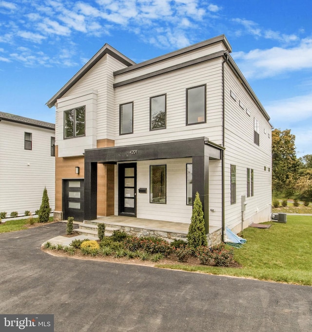 contemporary house featuring a front yard, cooling unit, and covered porch