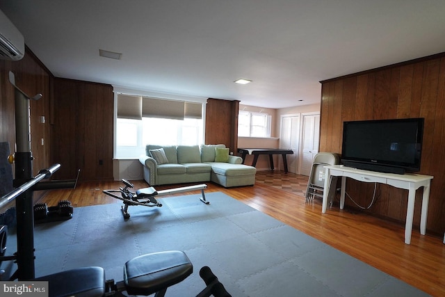 living room featuring a wall mounted AC, light wood-type flooring, and wooden walls