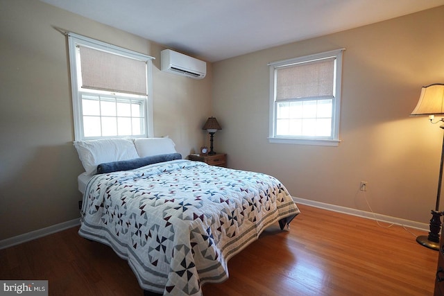 bedroom featuring a wall unit AC, wood-type flooring, and multiple windows