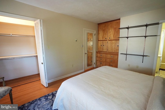 bedroom with wood-type flooring, ensuite bath, and a closet