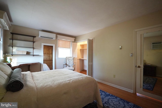 bedroom with wood-type flooring, a closet, and a wall mounted AC