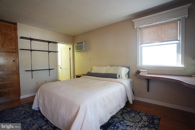 bedroom with a wall unit AC and dark wood-type flooring