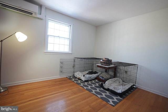 living area with a wall unit AC and hardwood / wood-style flooring