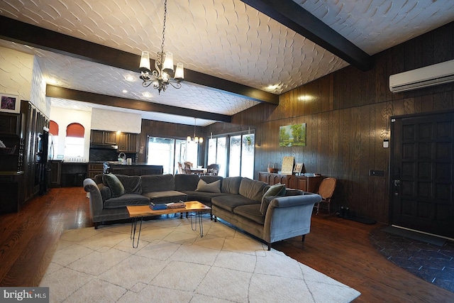 living room featuring wood-type flooring, a wall mounted AC, wooden walls, beam ceiling, and an inviting chandelier