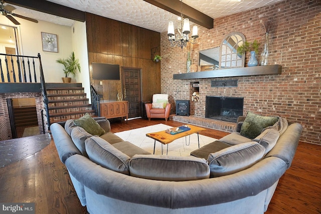 living room featuring a large fireplace, wood-type flooring, brick wall, wooden walls, and beam ceiling