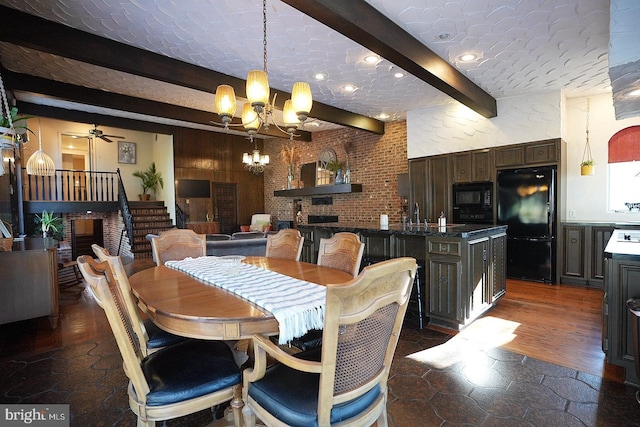 dining room with ceiling fan with notable chandelier, brick wall, beam ceiling, and sink