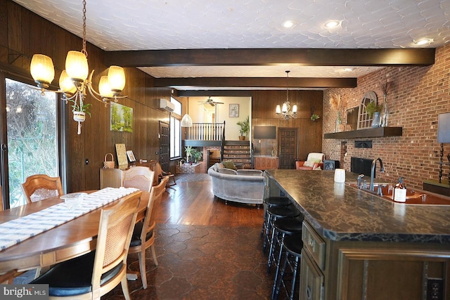 kitchen with a brick fireplace, wood walls, and beamed ceiling