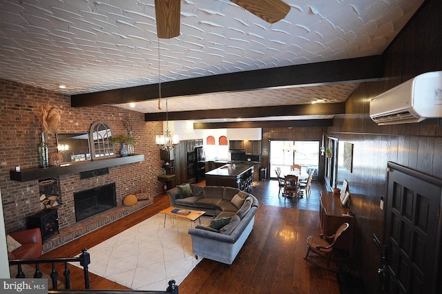 tiled living room with a chandelier, a wall unit AC, brick wall, a fireplace, and beam ceiling