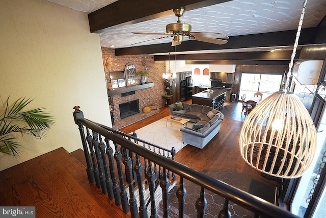 living room featuring brick wall, beam ceiling, ceiling fan, and a fireplace