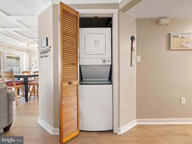 washroom with light hardwood / wood-style flooring and stacked washer / dryer